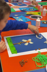 Un bambino della Scuola dell'Infanzia impegnato nella realizzazione di un collage polimaterico nel laboratorio di arte