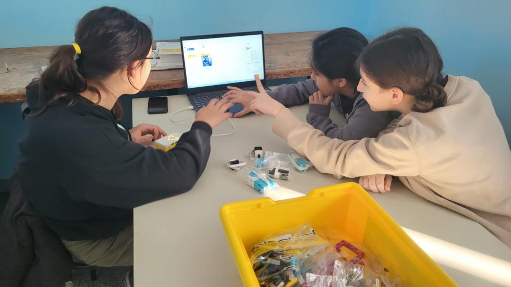 Nel laboratorio di robotica tre ragazze sono impegnate nello studio della programmazione di un robot